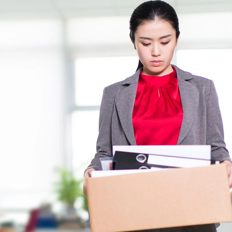 APAC woman carrying a box of personal work items