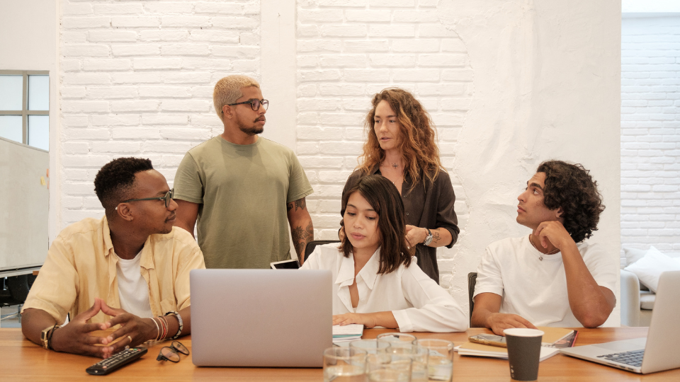 A work team gathers around a computer to plan their next steps.